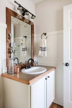 a bathroom with a sink, mirror and towel hanging on the wall next to it