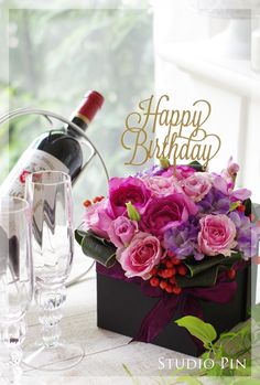 a wine bottle and some glasses on a table with a birthday card in the background