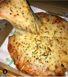 a pizza sitting on top of a box covered in cheese