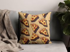 a pillow with pizza slices on it sitting on a couch next to a potted plant