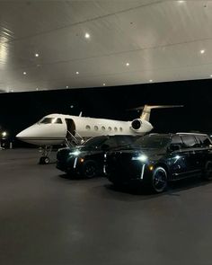 two cars parked in front of a private jet and an airplane on the tarmac