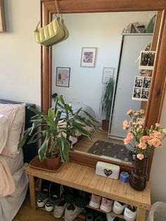 a mirror sitting on top of a wooden shelf next to a bed with shoes underneath it