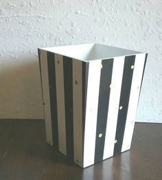 a black and white striped box sitting on top of a wooden table next to a wall