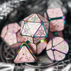 a group of pink and green dices sitting on top of a silver plate covered in holographic foil