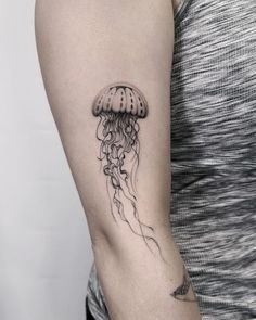 a black and white photo of a jellyfish tattoo on the left upper half of the arm