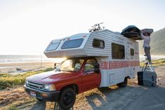 a man standing on the roof of a truck next to a camper with an awning