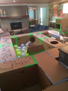 a young child playing with balloons in a cardboard box on the floor of a living room