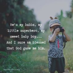 a little boy holding a camera up to his face with the caption he's my bubba, my little superhero, my sweet baby boy and i sure am blessed that god gave me him