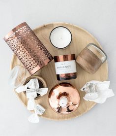 candles and other items are arranged on a wooden platter with white napkins around it