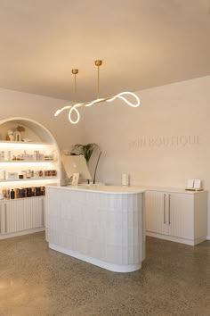 the front desk of a skin boutique with lights above it and shelves on either side