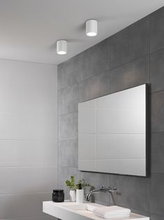 a white sink sitting under a bathroom mirror next to a wall mounted faucet