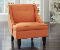 an orange chair sitting on top of a hard wood floor in front of a window