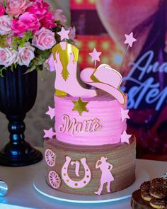 a pink and brown birthday cake sitting on top of a table next to a vase with flowers