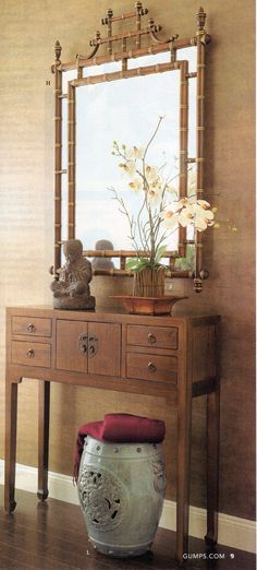 a mirror sitting on top of a wooden table next to a vase filled with flowers