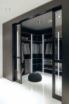 a walk in closet with mirrored doors and black furniture, along with an ottoman on the floor