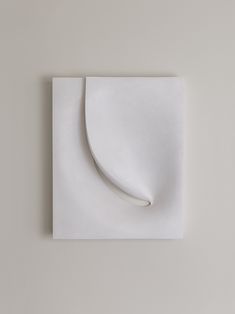 an abstract white paper sculpture on a gray wall with a curved corner in the center