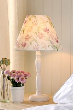 a lamp that is sitting on a table next to a vase with flowers in it