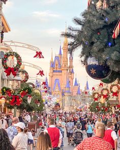 people are walking down the street in front of christmas decorations and castle at disney world