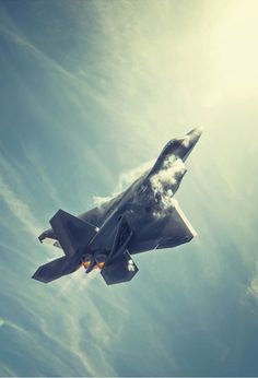 a fighter jet flying through the air with clouds in the sky behind it on a sunny day