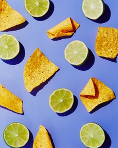 some limes and chips on a blue surface with one slice cut in half to look like a lemon