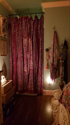 a room with a bed, lamp and red curtain