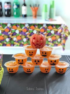 a table topped with lots of orange cups filled with liquid and jack - o'- lanterns