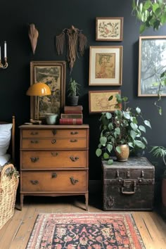 a room with black walls and lots of pictures on the wall, including an antique chest of drawers