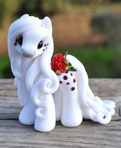 two white pony figurines sitting on top of a wooden table next to each other