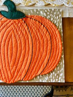 an orange quilted pumpkin sitting on top of a table