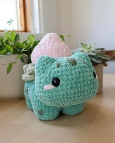 a crocheted stuffed animal sitting on top of a table next to a potted plant