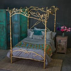 a gold metal bed with pillows and blankets on it's headboard, next to a green door