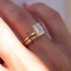 a woman's hand with a diamond ring on top of her finger and an engagement band