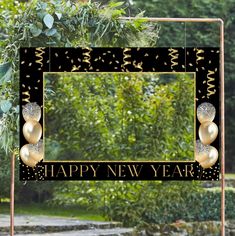 a black and gold new year's photo frame with two balloons hanging from it