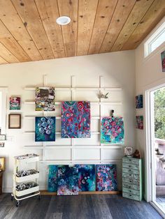 a room filled with lots of paintings on the wall next to a dresser and window