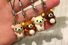 four little teddy bears are hanging from a keychain on a person's hand