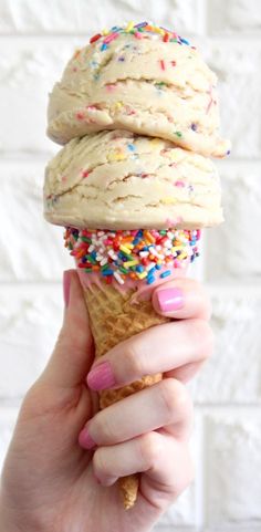 a hand holding an ice cream cone with sprinkles