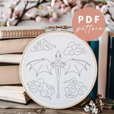 a cross stitch pattern with an image of a dragon in the sky on top of some books