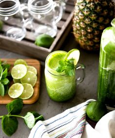 a pineapple drink with limes and mint on the side