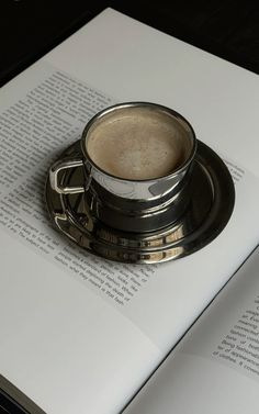 a cup of coffee sitting on top of an open book