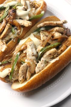 two sandwiches are on a white plate with green peppers and mushrooms in them, sitting next to each other