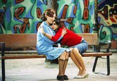 two women hugging each other on a bench