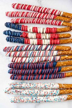 patriotic straws are lined up in rows on a white surface with red, white and blue sprinkles