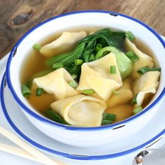 a bowl filled with dumplings and broccoli on top of a white plate