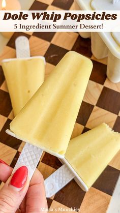 a person holding an ice cream popsicle on top of a checkered table