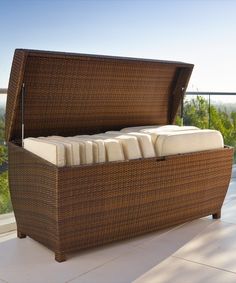 a wicker bed sitting on top of a patio next to a large glass window