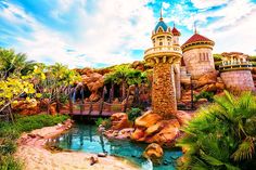 an amusement park with a tower and water feature in the middle, surrounded by palm trees