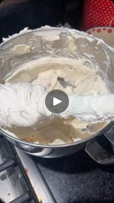 a metal pan filled with white frosting on top of a counter next to a keyboard