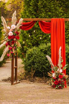 an outdoor ceremony with red drapes and flowers