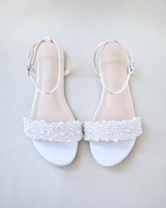 a pair of white shoes with pearls on them