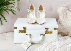 a pair of white shoes sitting on top of a white suitcase